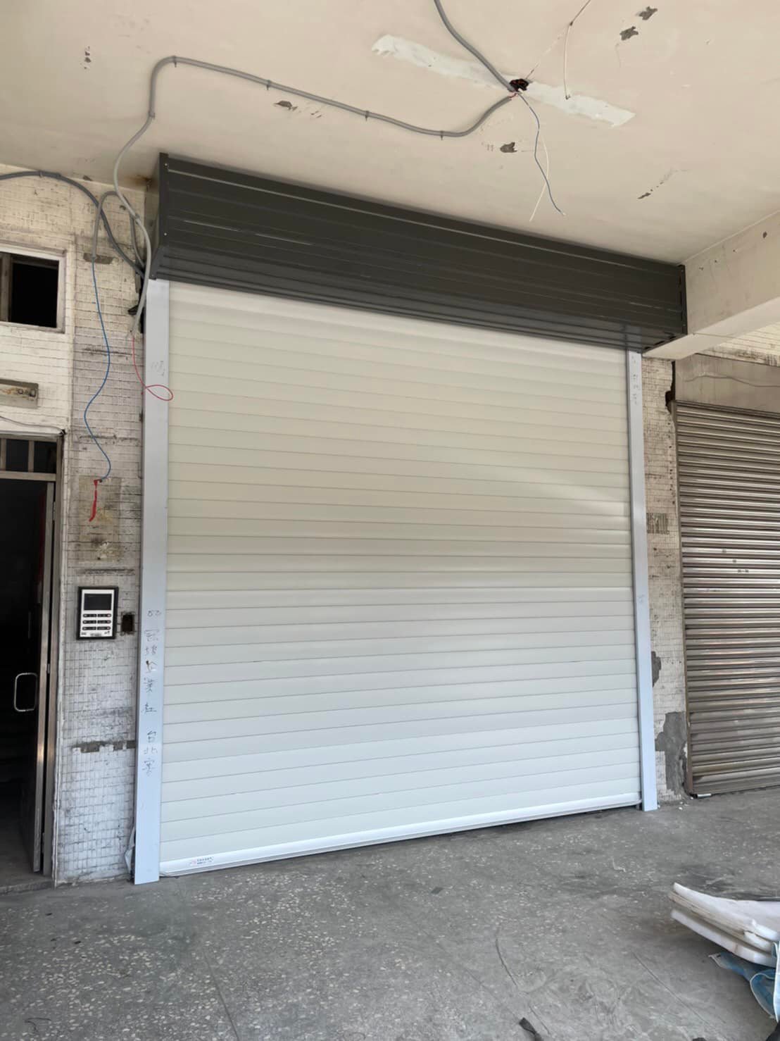 台北客人店面正在裝潢2樘舊式傳統門使用年份已久，店面又是整個新裝潢客人決定更換良輝平面型雙層鋁合金白色門板配上鐵灰捲箱整個不一樣的美感。先行趕工一樘讓其他工程同步進行後續旁邊在約時間來施工。